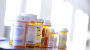 A collection of orange pill bottles arranged on a countertop in front of a window